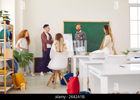 L'insegnante con lavagna conduce una lezione per gli studenti, spiegando loro il materiale educativo. Foto Stock