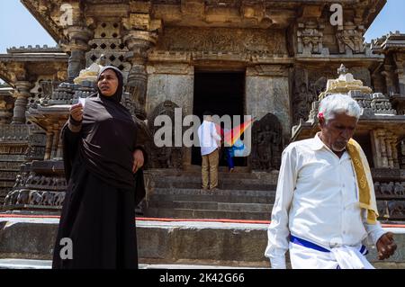 Halebid, Karnataka, India: Un uomo e una donna si trovano fuori dal tempio di Hoysaleswara del 12th° secolo. Foto Stock