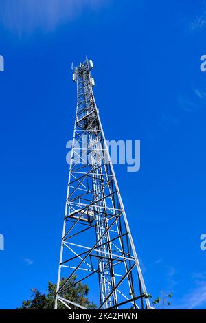 Alta torre di telecomunicazioni contro un cielo blu Foto Stock