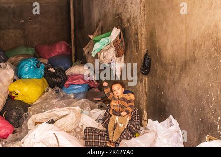 Manshiyat Naser, Città spazzatura, il Cairo, Egitto. Febbraio 14, 2022. Madre che tiene in mano il suo bambino giovane mentre elabora i sacchetti di immondizia in NAS di Manshiyat Foto Stock