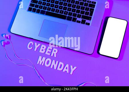 Immagine del testo cyber lunedì, smartphone con spazio copia, computer portatile e auricolari al neon viola Foto Stock