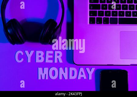 Immagine di testo cyber lunedì, smartphone, computer portatile e cuffie su sfondo viola al neon Foto Stock
