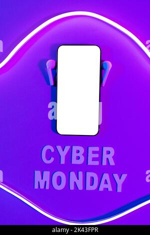 Immagine del testo del cyber lunedì, smartphone con spazio per la copia e auricolari su sfondo viola al neon Foto Stock