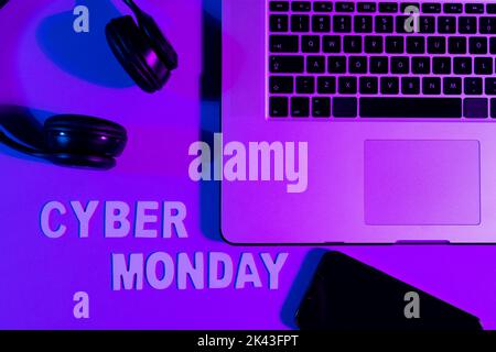 Immagine di testo cyber lunedì, smartphone, computer portatile e cuffie su sfondo viola al neon Foto Stock