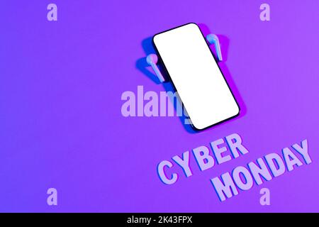 Immagine del testo del cyber lunedì, smartphone con spazio per la copia e auricolari su sfondo viola al neon Foto Stock