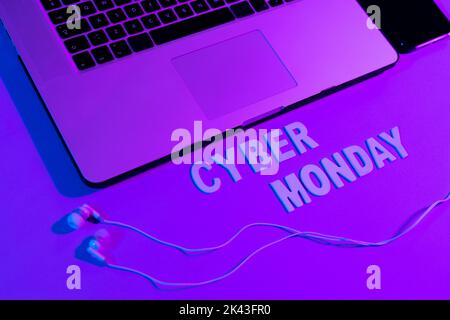 Immagine del cyber lunedì testo, smartphone, computer portatile e auricolari al neon viola Foto Stock