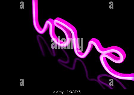 Immagine di un vivace testo amore al neon formato da bacchette rosa su sfondo nero e spazio copia Foto Stock