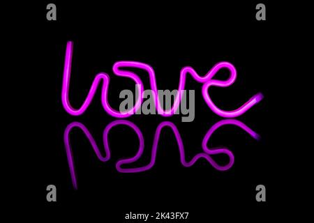 Immagine di un vivace testo amore al neon formato da bacchette rosa su sfondo nero e spazio copia Foto Stock