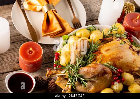 Vista dall'alto del tavolo del ringraziamento con pollo arrosto, verdure, candele e decorazione autunnale Foto Stock