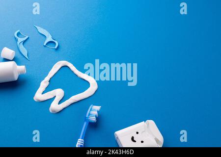 Immagine di spazzolino da denti, dentifricio, filo, liquido e dente in pasta su superficie blu Foto Stock
