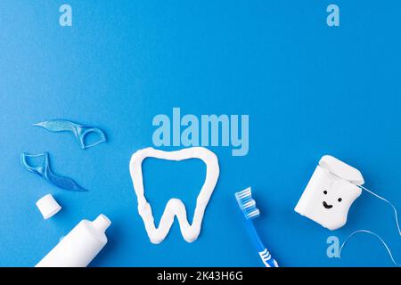 Immagine di spazzolino da denti, dentifricio, filo, liquido e dente in pasta su superficie blu Foto Stock