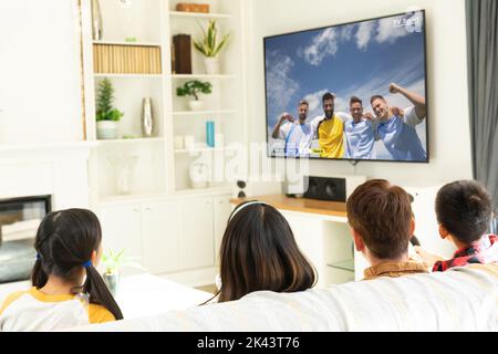 Diversi bambini che guardano la tv con una partita di calcio sullo schermo Foto Stock