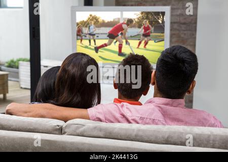 Vista posteriore di famiglia felice guardando la tv sul divano Foto Stock