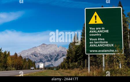 Un segnale di avvertimento valanghe lungo la Trans Canadian Highway scritto in inglese e francese a Banff, Alberta, Canada Foto Stock