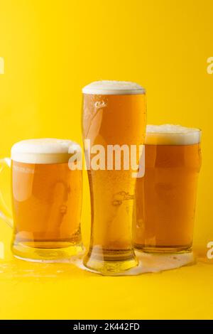 Immagine di tre diversi bicchieri di birra lager, con spazio copia su sfondo giallo Foto Stock