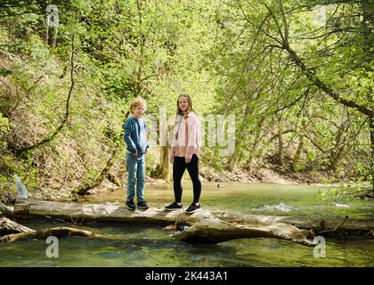 Ritratto di fratello (10-11) e sorella (12-13) in piedi sul lago di log on Foto Stock