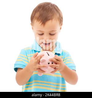 Si sente così pieno. Foto studio di un ragazzo che guarda una banca di piggy isolato su bianco. Foto Stock