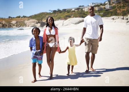 Godendo la sabbia tra le dita dei piedi. Una famiglia afro-americana che si gode una giornata in spiaggia insieme. Foto Stock