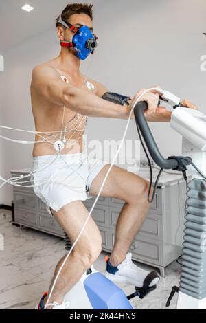 Uomo che esamina il suo sistema cardiovascolare su simulatore di bici Foto Stock