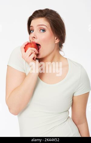 Delizioso. Bella donna brunette prendere un morso da una mela. Foto Stock