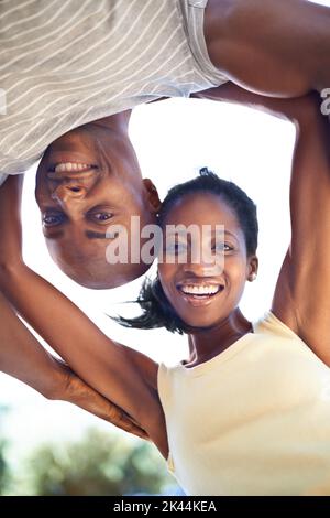 Sorrisi brillanti e atteggiamenti positivi. Una giovane coppia africana felice che guarda giù la macchina fotografica con i sorrisi ampi. Foto Stock