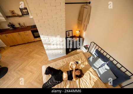 Donna con smartphone a letto a casa Foto Stock