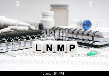 Concetto di medicina. Sulla tabella sono riportati diari, farmaci e cubi con l'iscrizione LNMP Foto Stock