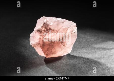 Campione grezzo di quarzo rosa non tagliato, retroilluminato da dietro su sfondo scuro. Collezione di pietre minerali Foto Stock