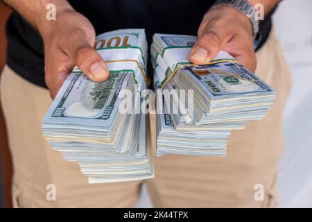 Pacchetti di dollari americani nelle mani di un uomo d’affari. Messa a fuoco selettiva Foto Stock