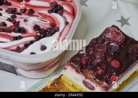 Gelato con mirtilli rossi e ciliegie in scatola e torta con bacche sul tavolo Foto Stock