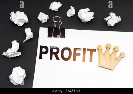 Concetto di business e finanza. Su sfondo nero, carta stropicciata e un foglio con l'iscrizione - PROFITTO Foto Stock