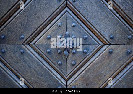 Particolare di una vecchia porta in legno con tradizionale pomello in metallo. Foto Stock