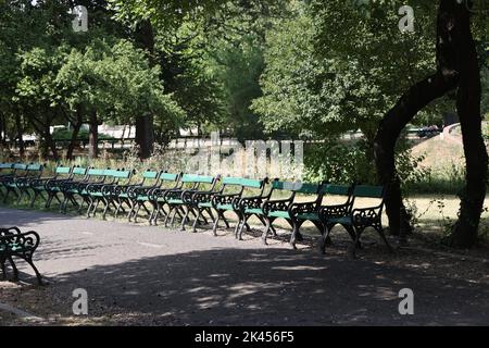 Lunga fila di sedie storiche (vuote) nel parco di Cișmigiu a Bucarest, Romania Foto Stock