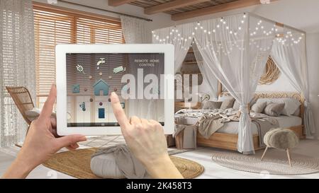 Sistema di controllo della casa con telecomando intelligente su un tablet digitale. Dispositivo con icone app. Camera da letto in legno bohémien in stile bohémien. Letto a baldacchino sullo sfondo, arco Foto Stock