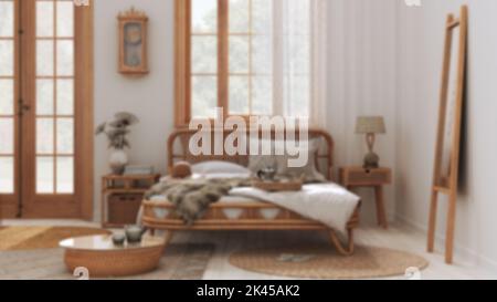 Sfondo sfocato, camera da letto casale boho chic con letto matrimoniale e mobili in rattan. Tappeti e decorazioni in iuta. Carta da parati Country, interni bohémien des Foto Stock