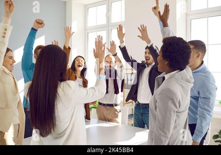 Felice eccitato team di business diversi per celebrare il successo, alto pugno e ridere Foto Stock