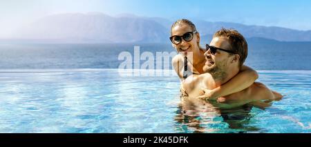 coppia felice innamorata divertirsi insieme nella piscina infinity con vista mare presso il resort per adulti. vacanza estiva romantica. viaggio di nozze. banner w Foto Stock