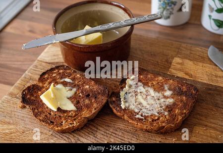 Pane tostato al granaio marrone con burro per la colazione inglese Foto Stock