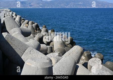 Vista ravvicinata sulle pietre di cemento tetrapod breakwater accumulate in un rompicapo a onde per proteggere il porto di Heraklion. Foto Stock