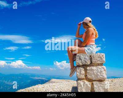 Giovane ragazza seduta su una pietra con una bella vista dalla cima del Mont Ventoux Foto Stock