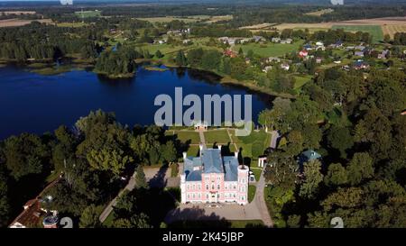 Vista aerea del Palazzo Birinu. Castello lettone sul lago con Nizza Giardino, Drone Shot. Birini Manor, Regione di Vidzeme, Lettonia. Soleggiato Autunno Foto Stock