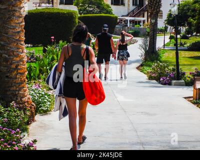 persone che camminano dalla spiaggia alle loro camere dopo una giornata di sole in egitto Foto Stock