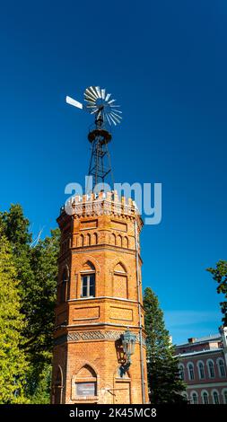 Old Red Brick Water Tower Mulino a vento Meteo Vane. Vista all'alba di una vecchia e abbandonata Vane tempo Foto Stock