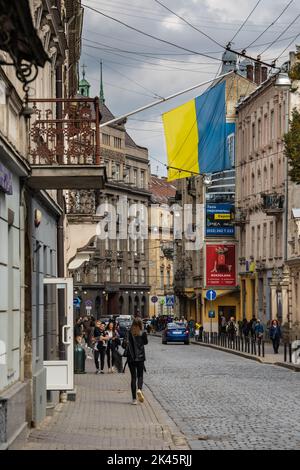 Bandiera Ucraina e scena di strada nella storica Lviv durante il tempo di guerra Foto Stock