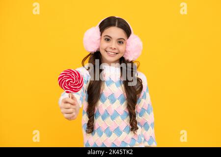 Bambino teen freddo con lollipop sopra sfondo isolato giallo. Dolce vita d'infanzia. Ragazza teen con caramella lollipop yummy. Foto Stock