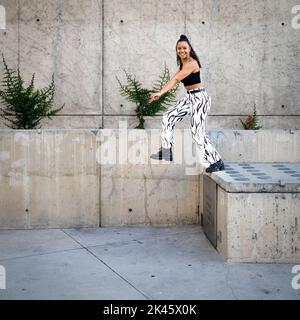 Sequenza di colpi di giovane donna nera felice che saltano fuori di un camminamento Foto Stock