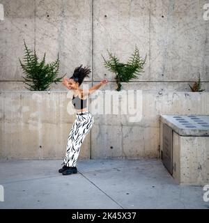 Sequenza di colpi di giovane donna nera felice che saltano fuori di un camminamento Foto Stock