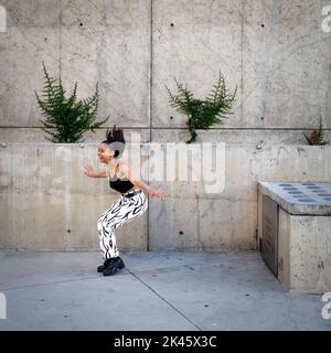 Sequenza di colpi di giovane donna nera felice che saltano fuori di un camminamento Foto Stock