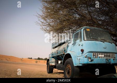 Un vecchio camion di trasporto dell'acqua abbandonato parcheggiato sotto l'albero nel deserto di Dubai Foto Stock