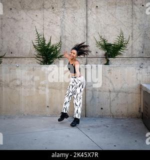 Sequenza di colpi di giovane donna nera felice che saltano fuori di un camminamento Foto Stock